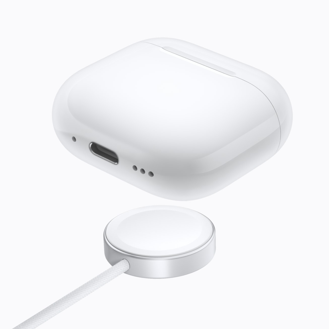 Les AirPods 5 officiels et leur boîtier de charge sans fil posé sur un chargeur.